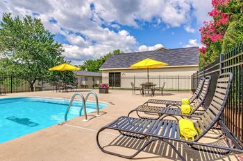 A pool area with a yellow umbrella and a black fence.